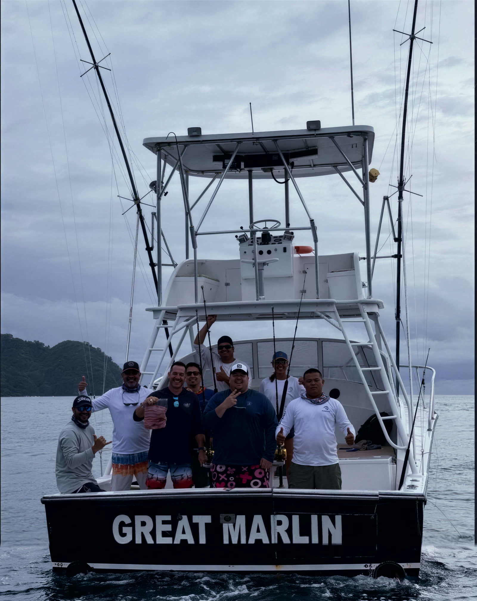 The Great Marlin at her mooring, tower and outriggers up, crew and guests on the stern, her name across the transom